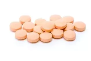ORANGE PILLS IN A PILE LAYING ON A SOLID WHITE BACKGROUND